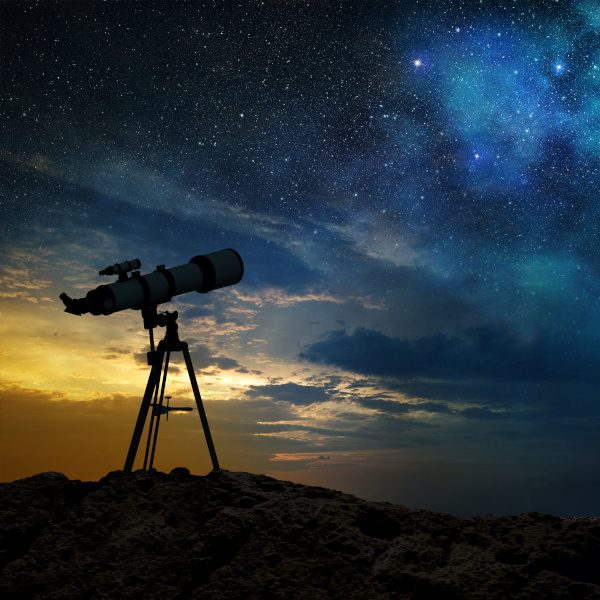 milky way at dawn and silhouette of a telescope